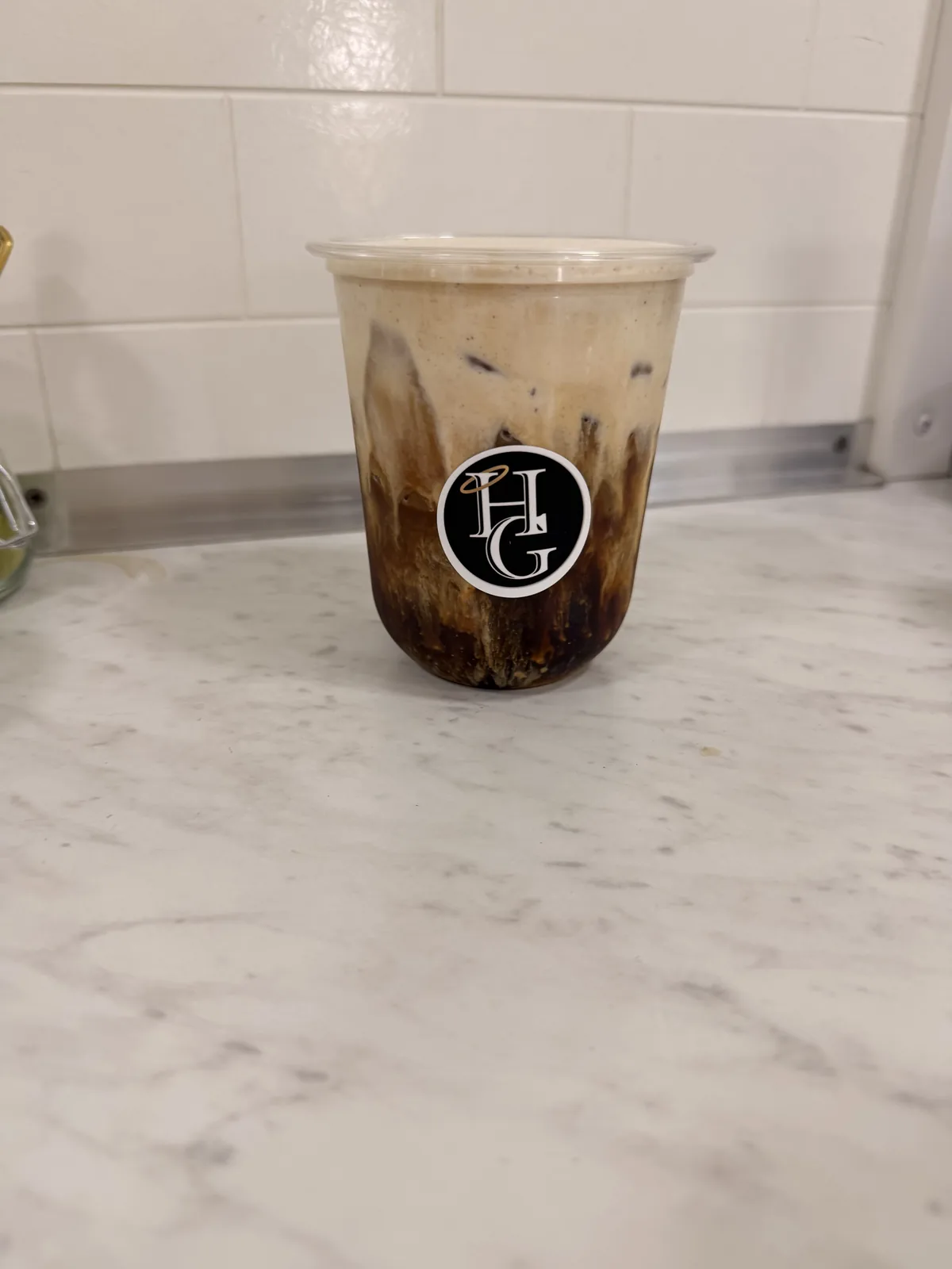 A layered iced Holy Grounds coffee in a branded clear cup