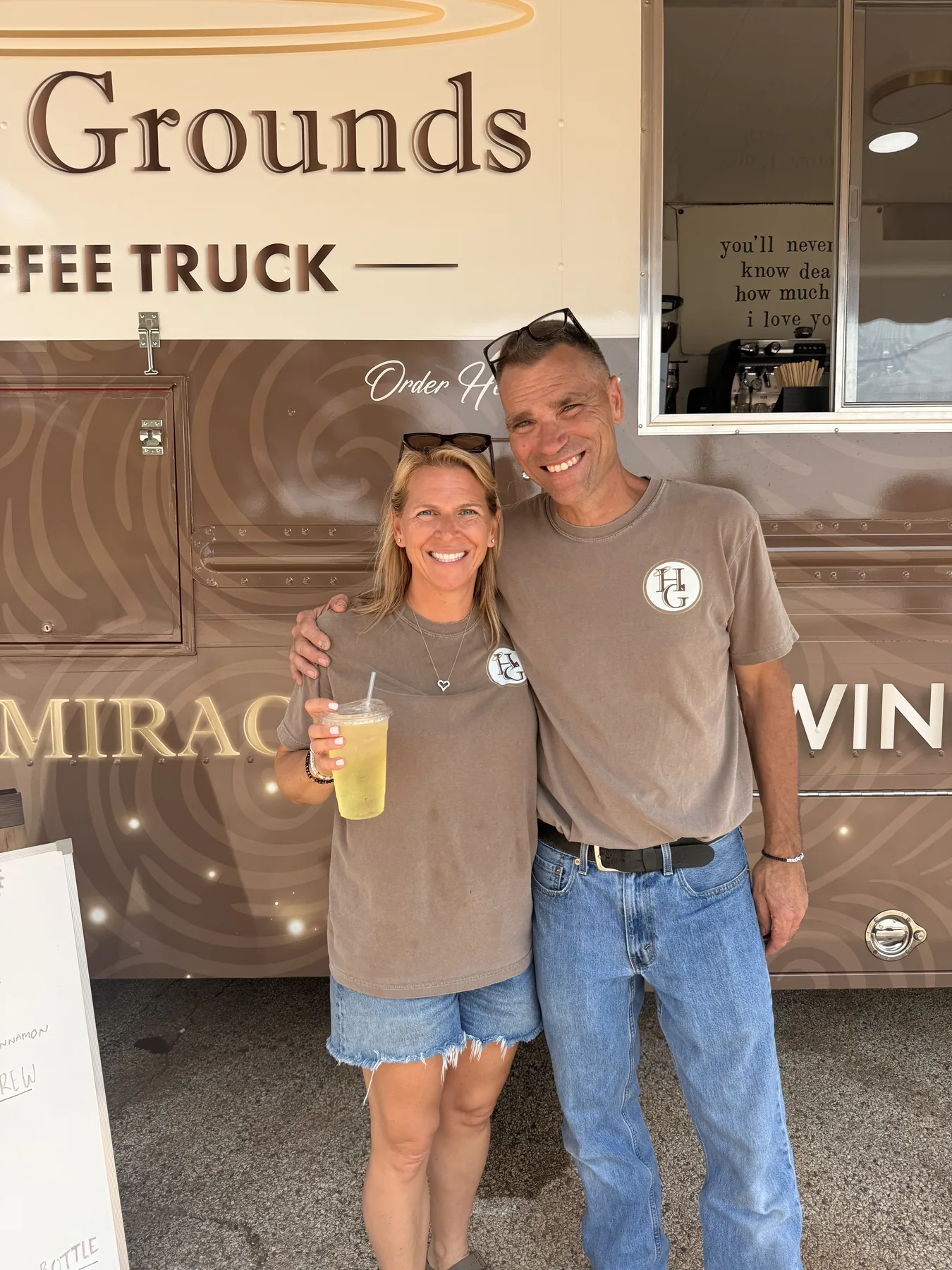 Two Holy Grounds team members in matching logo shirts standing together in front of the truck