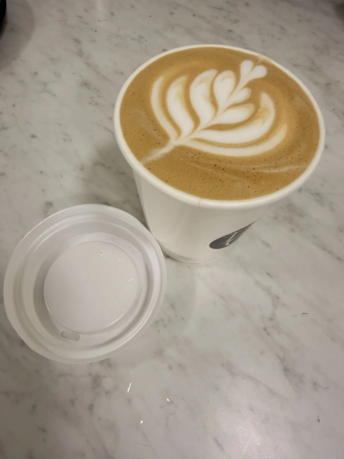 A hot Holy Grounds coffee topped with leaf-shaped latte art