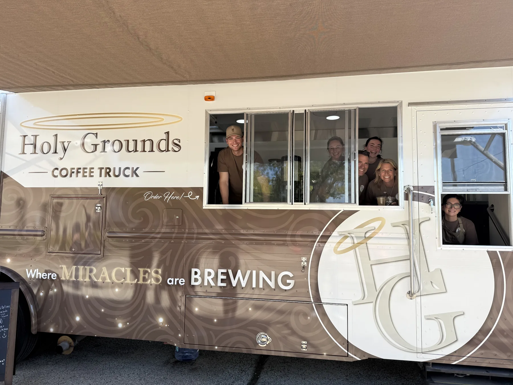 Holy Grounds team members smiling from the truck service windows